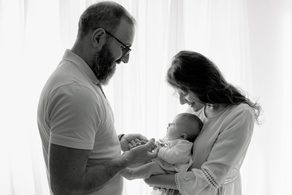 Photographie en noir et blanc d'un bébé et ses parents en contre jour